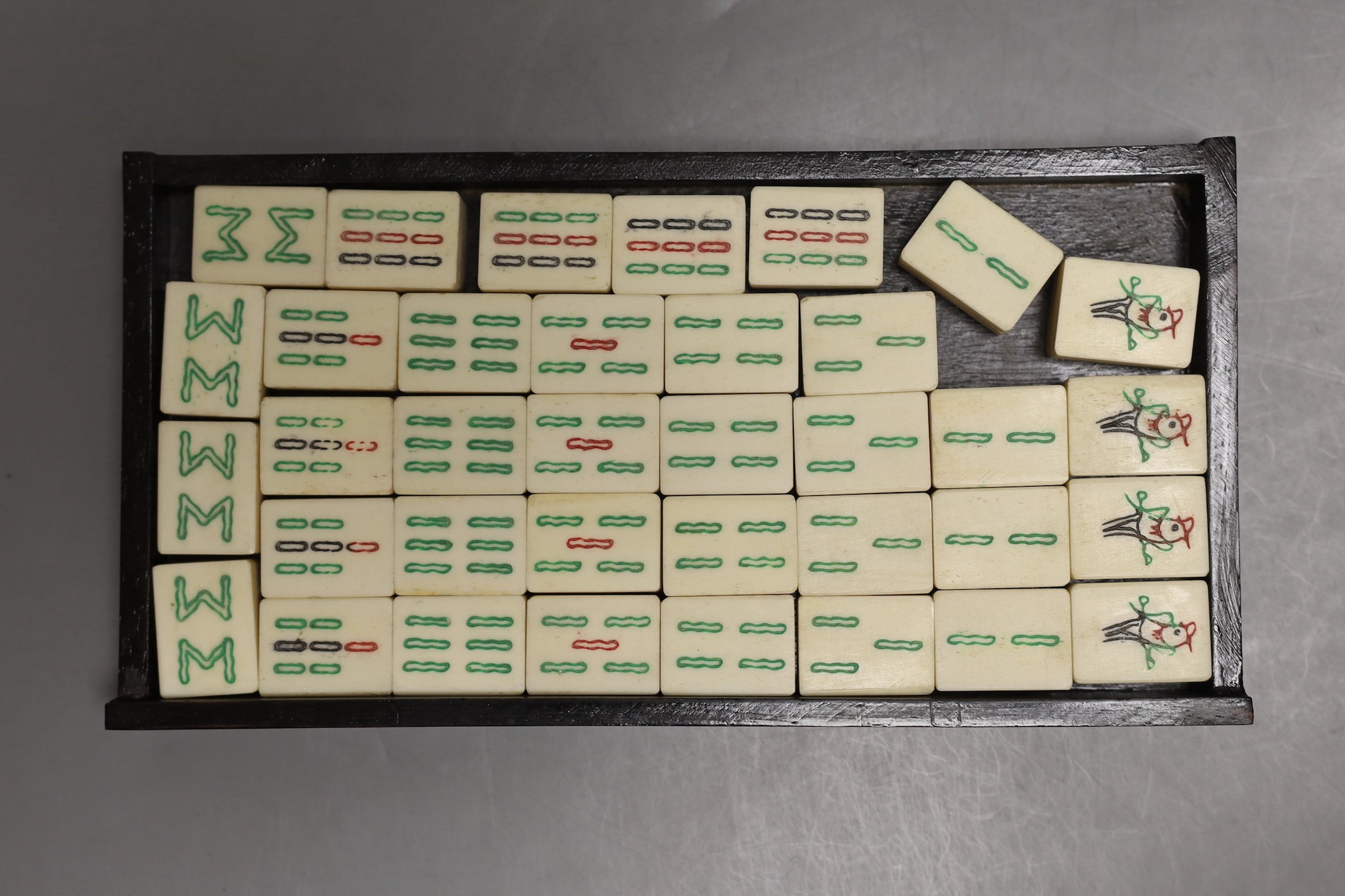 A Chinese boxed mahjong set, bone and bamboo gaming pieces, 24.5 cms wide x 16cms high.